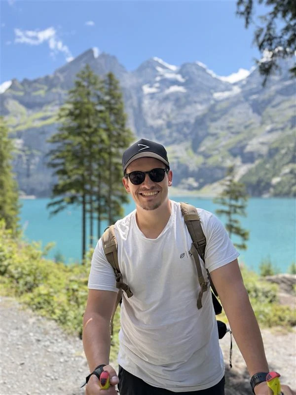 Paul Moos unterwegs in den Bergen, lächelnd vor einer Landschaft